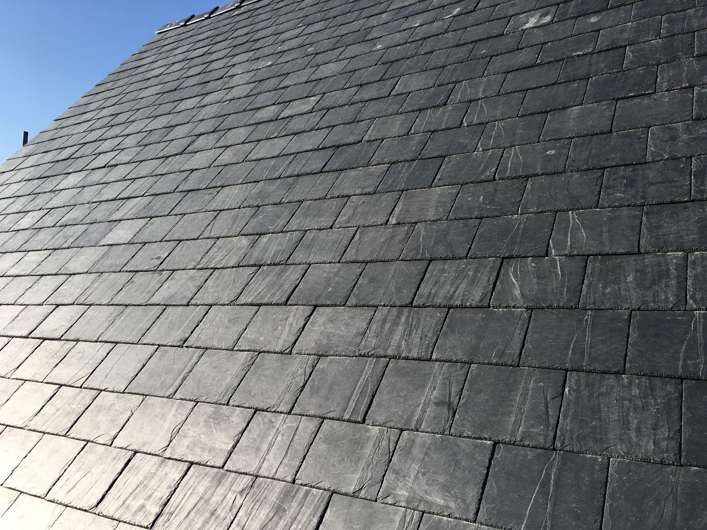 Close up of slate roof tiles with blue sky in background